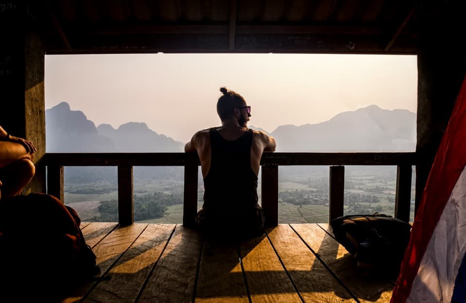 Someone sitting quietly at dawn, looking out over a misty valley