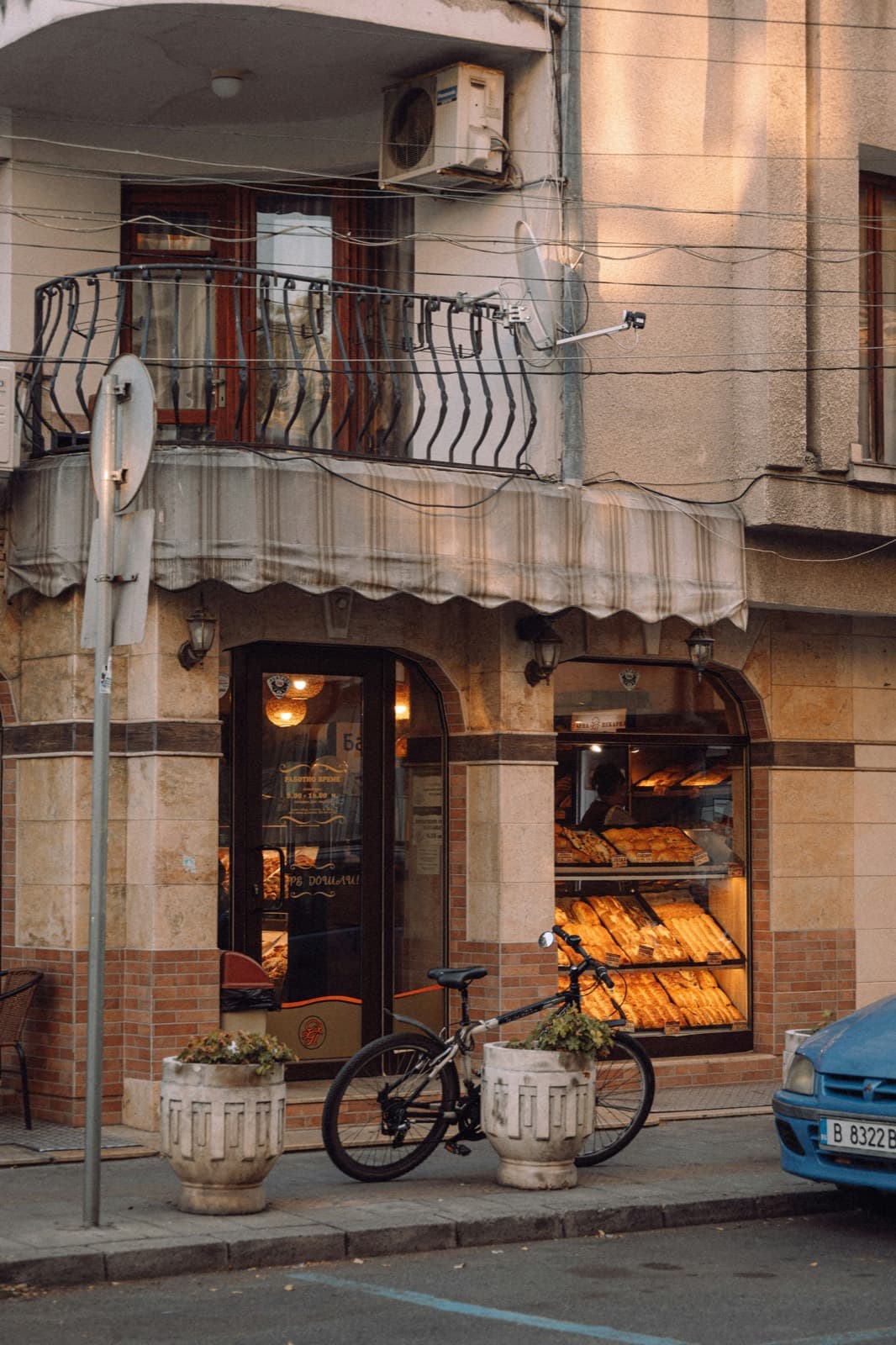 A corner bakery glowing at golden hour, a bicycle leaning under a wrought-iron balcony