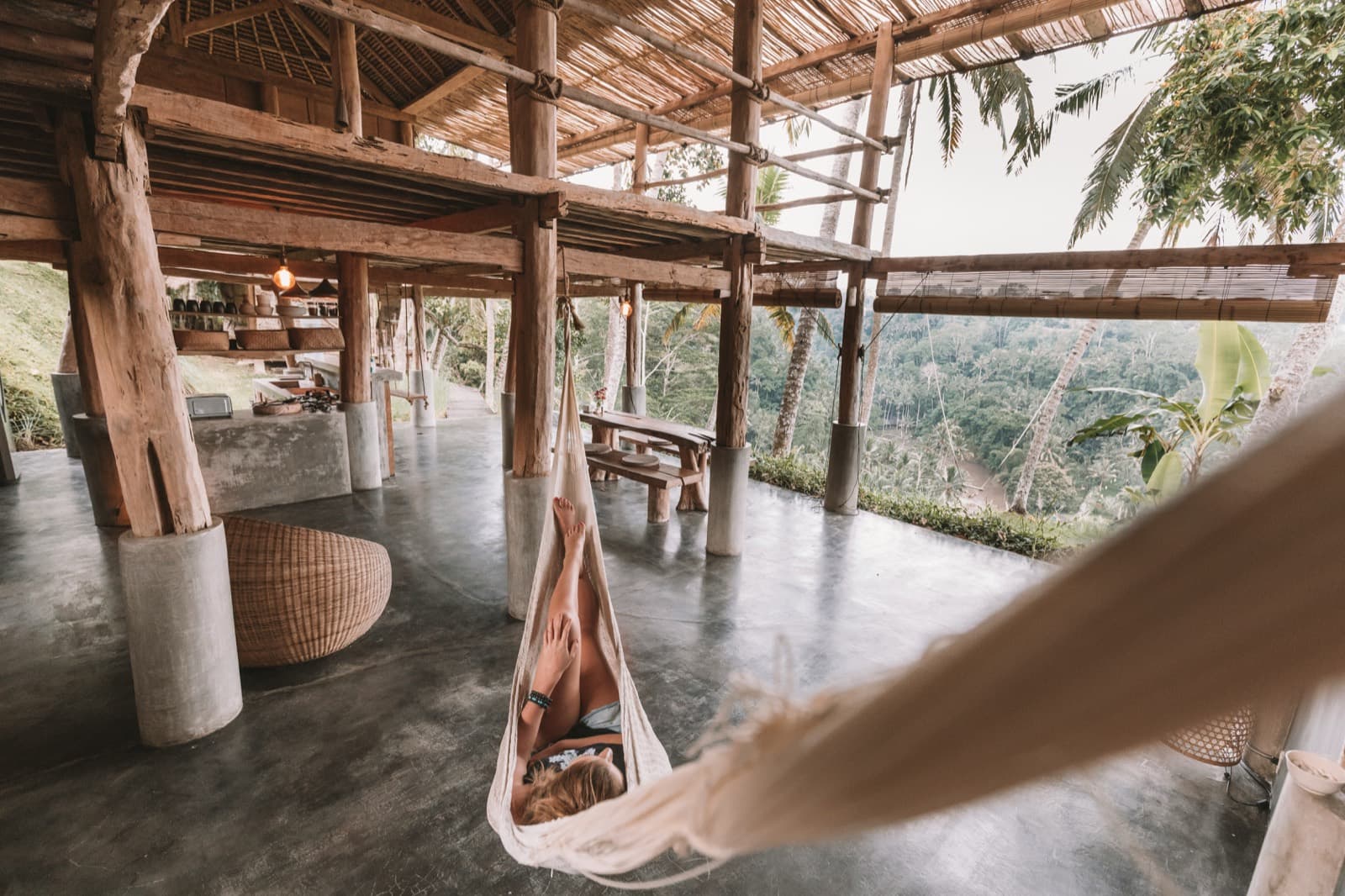 Someone lounging in a hammock inside an open bamboo house above the jungle